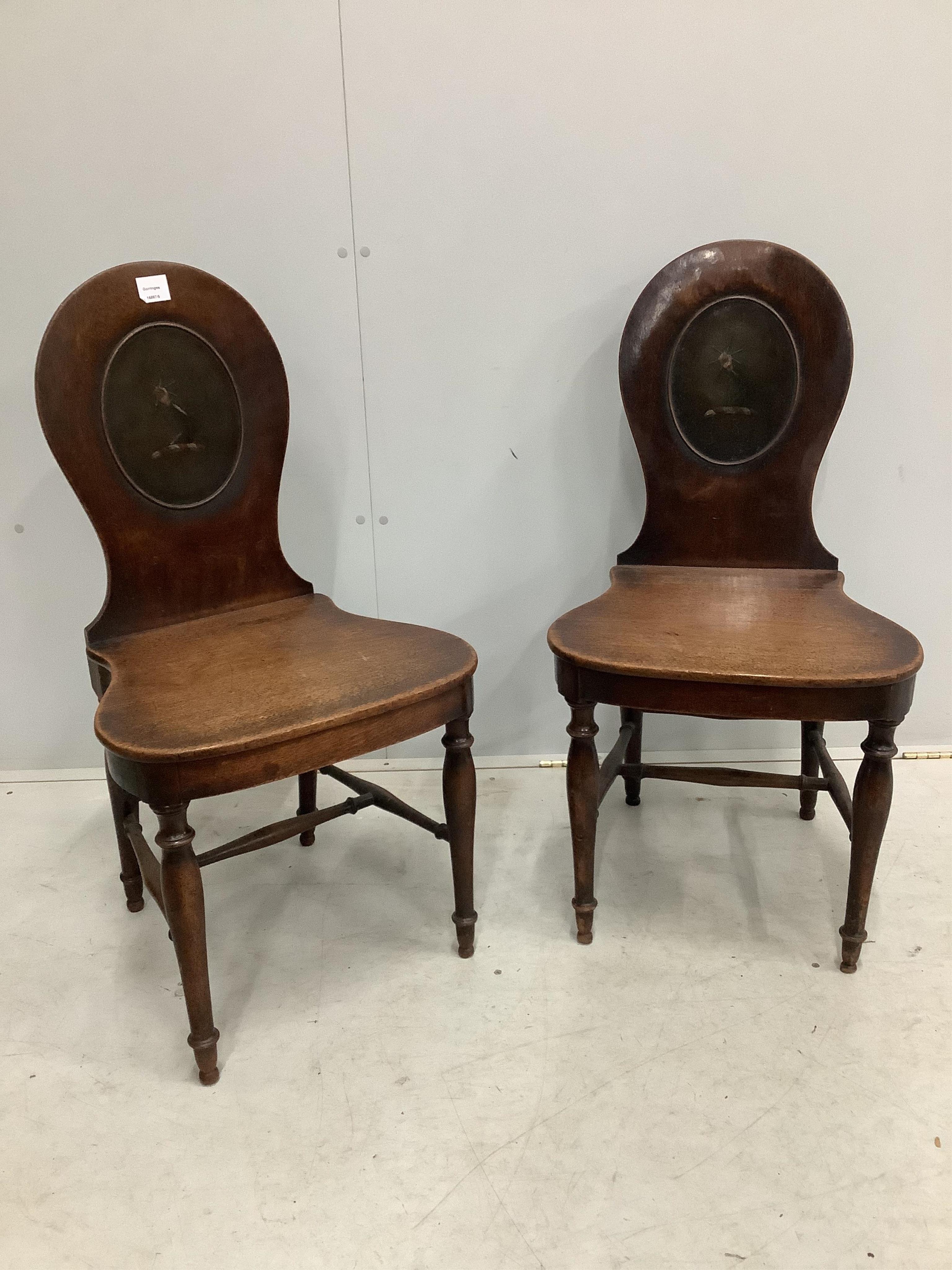 A pair of George III mahogany hall chairs with painted armorials, width 47cm, depth 42cm, height 92cm. Condition - fair